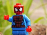 a lego spider - man is standing on a rock