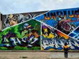 man in black jacket and black pants standing beside graffiti wall during daytime