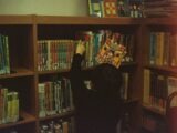 person in black long sleeve shirt standing near brown wooden shelf