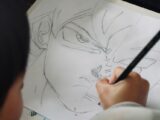 Child drawing anime character with pencil on paper