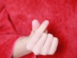 Close-up of hand making a popular gesture on a red background.