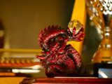 A detailed red dragon figurine with a crystal orb.