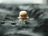 A miniature krillin figurine sits on gray fabric.