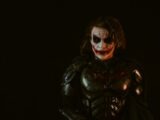 Man in joker costume with dark makeup and armor