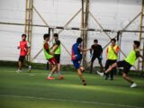 Young men playing soccer on an indoor field.
