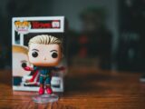 Small bright figure of toy character placed on timber table on blurred background