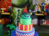 Vibrant superhero-themed birthday cake with a number four candle, perfect for kids' celebrations.