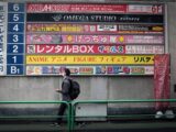 man in black jacket sitting on green metal bench