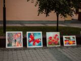 a row of paintings sitting on the side of a road