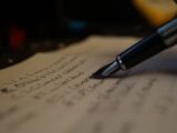 a person writing on a piece of paper with a pen
