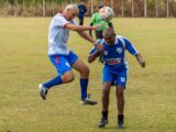Two men jump to head a soccer ball.