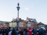 a crowd of people standing in front of tall buildings